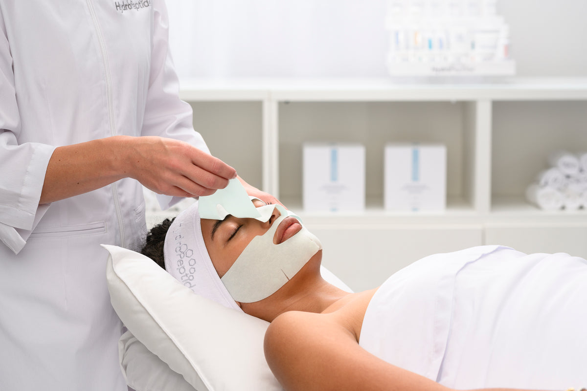 HydroPeptide-behandling på professionell klinik – specialist applicerar mask på kund